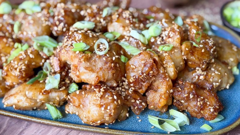 Close up of 1-wok sesame chicken on serving platter with scallion garnish