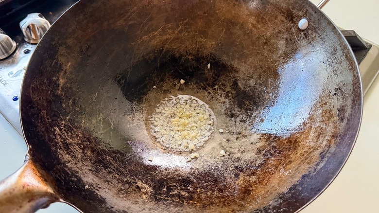 Minced garlic simmering in peanut oil in wok
