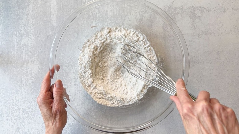 Whisking together dry ingredients for sesame chicken batter in large glass bowl
