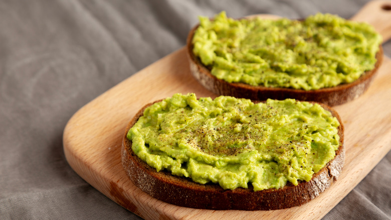 Avocado toast on cutting board with grey background