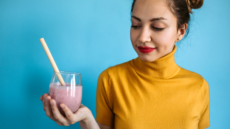 Woman holding a berry smoothie with a blue background