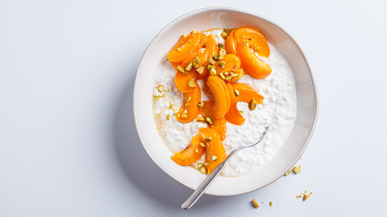 Bowl of cottage cheese with sliced peaches and nuts