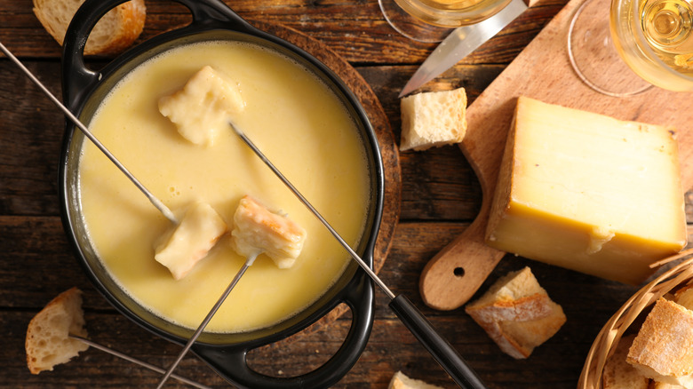 Guests dip bread into a fondue pot
