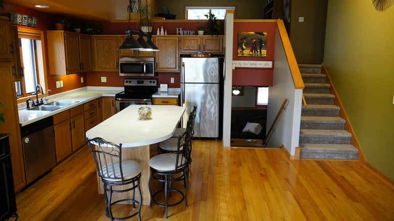 1990s home with kitchen in Wisconsin showing stainless steel fridge, white counters, and warm wood cabinets