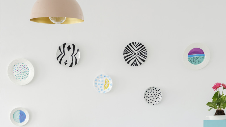 Plates on wall as decoration over table with flowers in vase