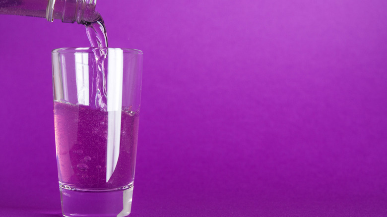 Pouring grape soda into a glass