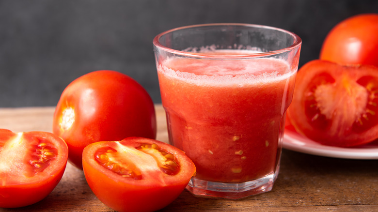 Glass of tomato juice surrounded by fresh tomatoes