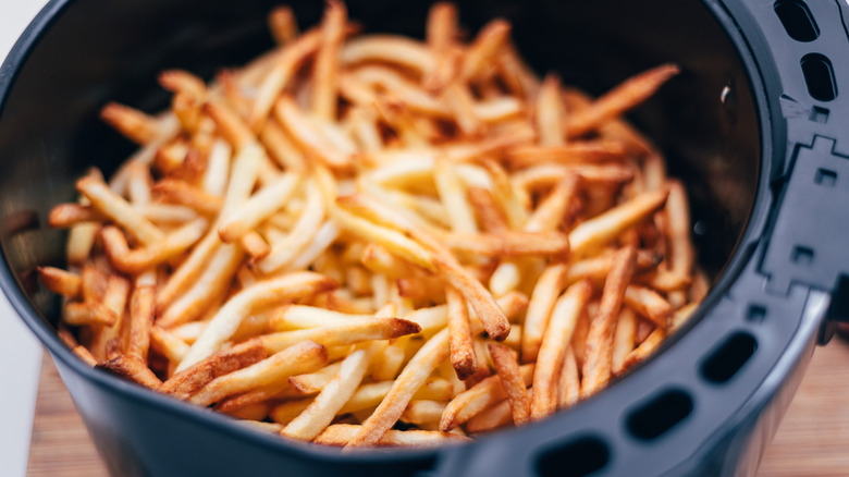 Fries piled in an air fryer basket