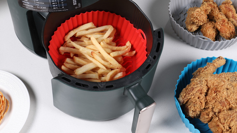 Silicone liner holding fries in an air fryer and liners on the side filled with fried chicken