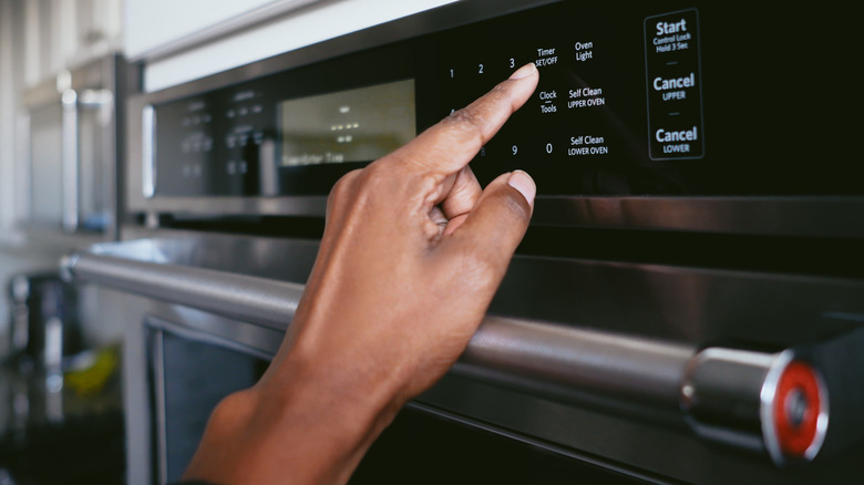 hand setting the temperature on an oven panel