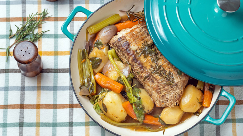 turquoise Dutch oven with meat and potatoes inside