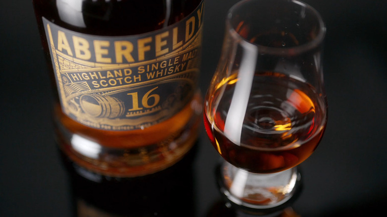 A bottle of Aberfeldy 16 Year Old and a glass of whisky on a rock