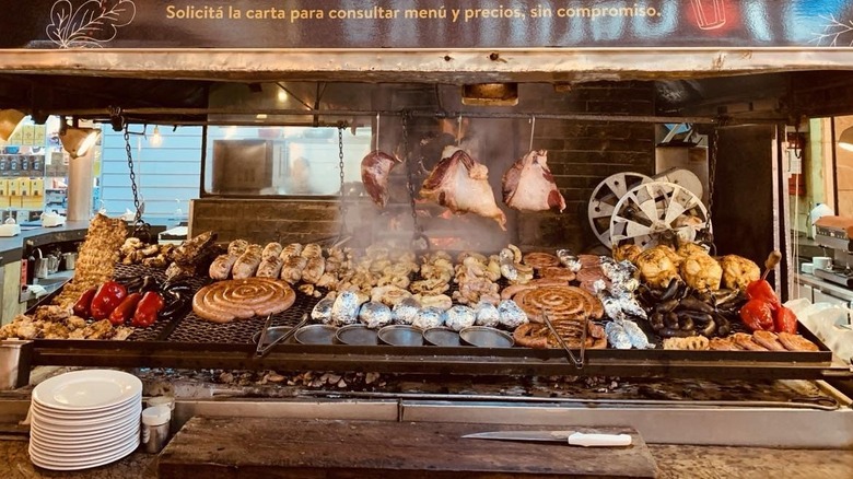 A parilla grill covered in cooking meats at Estancia del Puerto