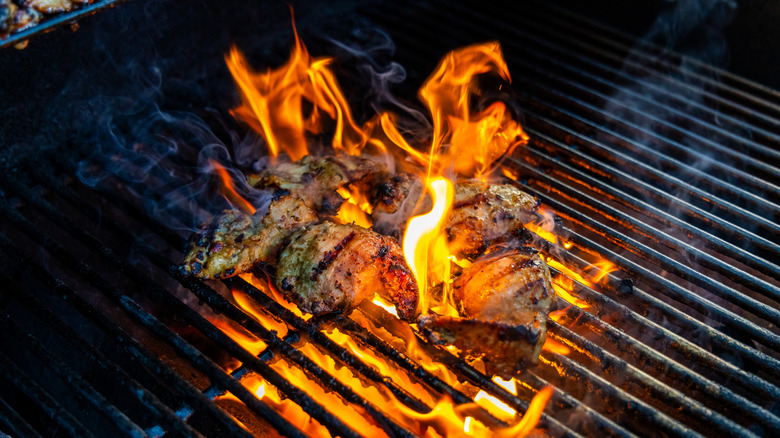 Meat on a grill with flames