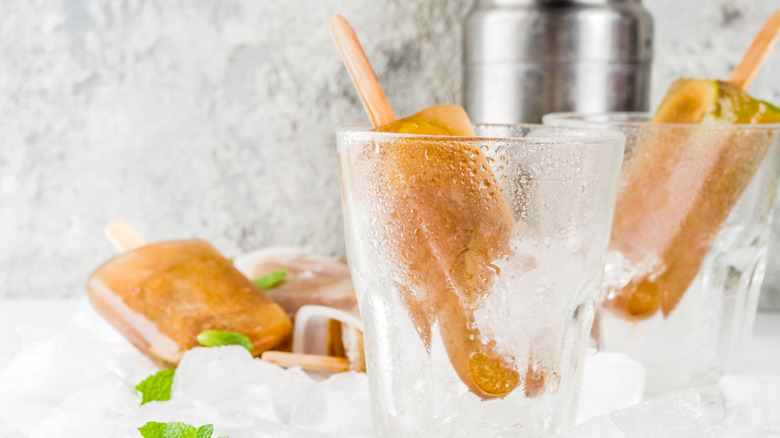 Frozen mint julet popsicles in ice cups with light gray wall in background.