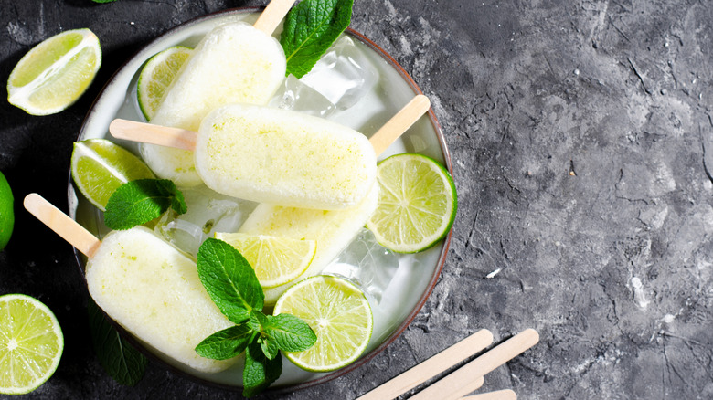 Lime and mint popsicles in bowl on dark gray countertop.