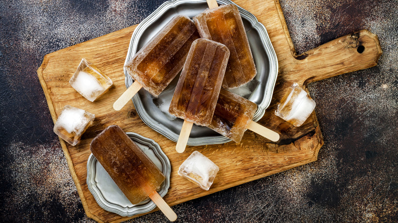 rum & coke popsicles on silver trays and wooden cutting board.