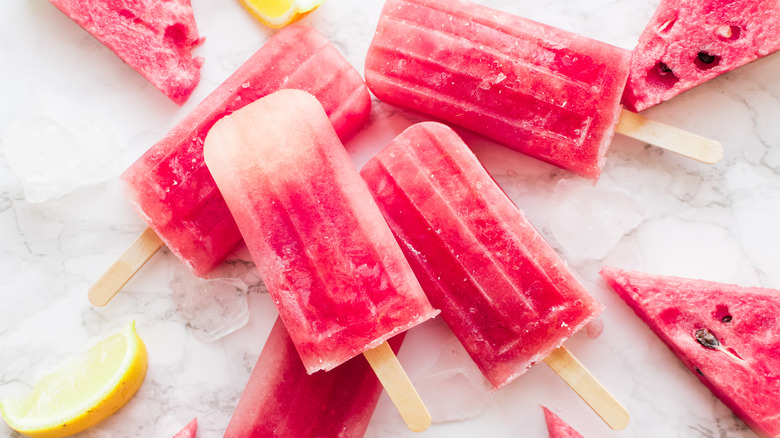Watermelon and lemon popsicles on white granite counter