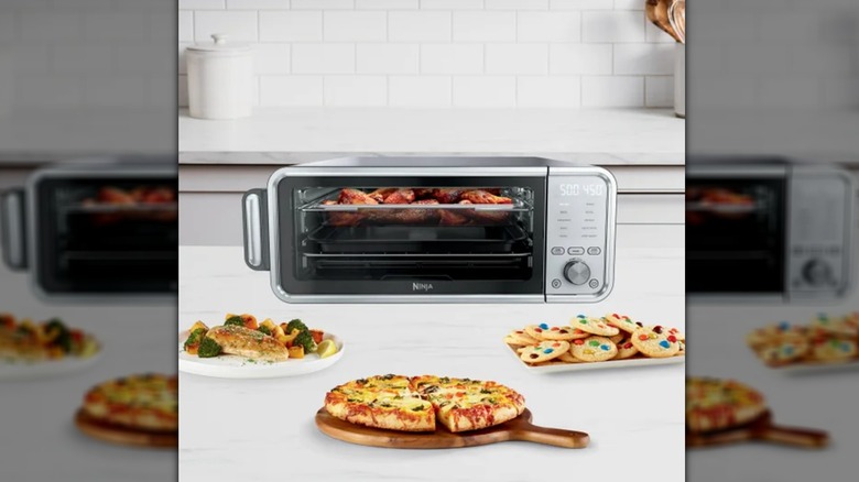 toaster/air fryer with pizza, cookies, and fish surrounding it