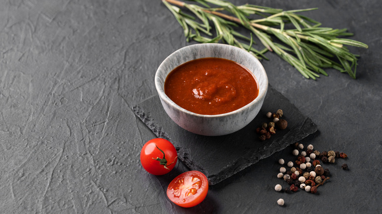 BBQ sauce on gray background with herbs and a grape tomato