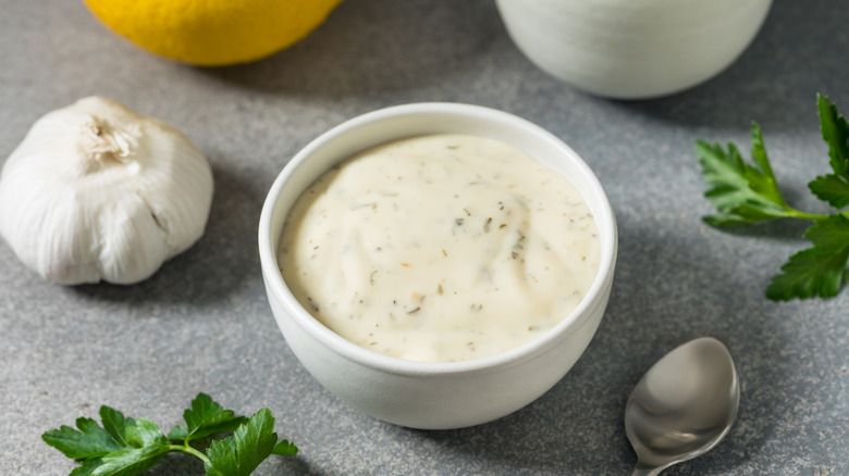 ramekin of homemade ranch dressing surrounded by ingredients and spoon