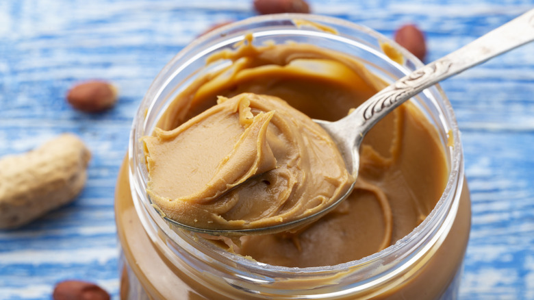 Spoon scooping peanut butter from jar.