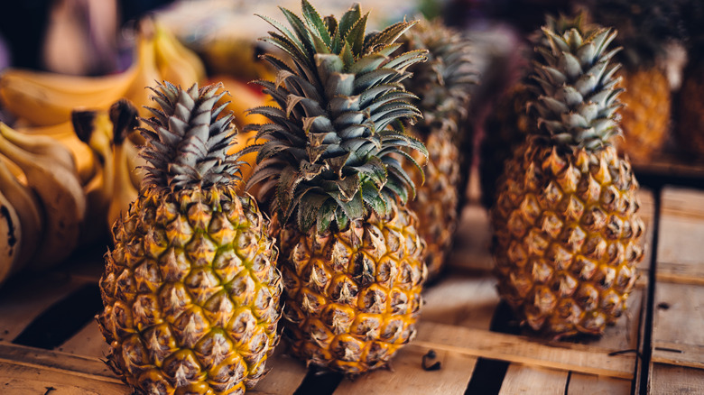 Several whole pineapples in a wooden crate