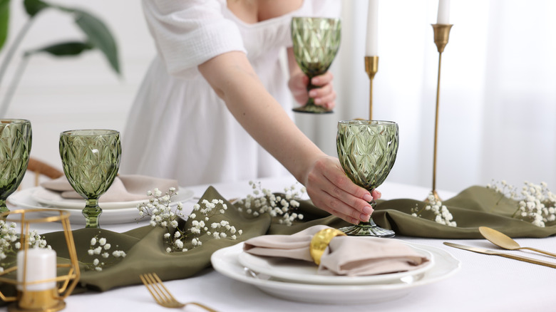 A person in a white dress setting an elegant table