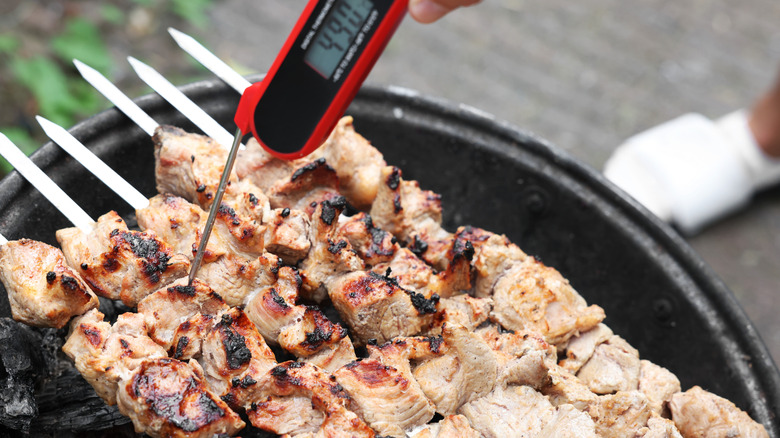 Chicken kebabs are checked with a meat thermometer