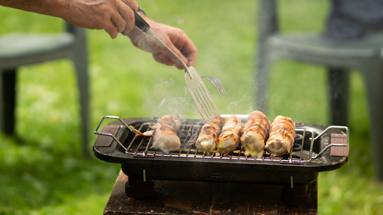 Chicken skewers are flipped on a grill