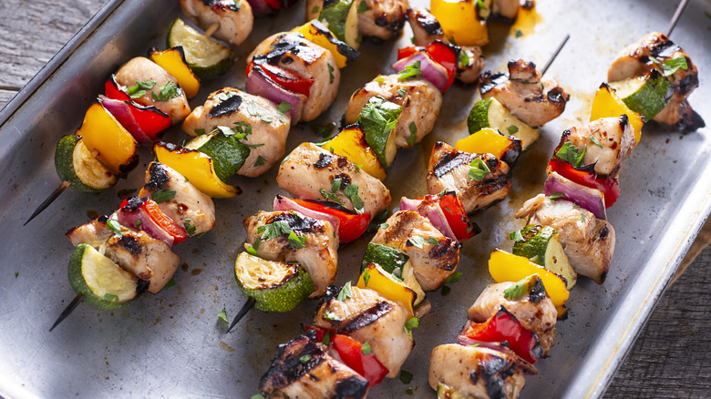 Chicken kebabs rest on a tray
