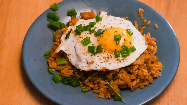 Fried rice topped with a sunny side up egg and chopped green onion on a plate