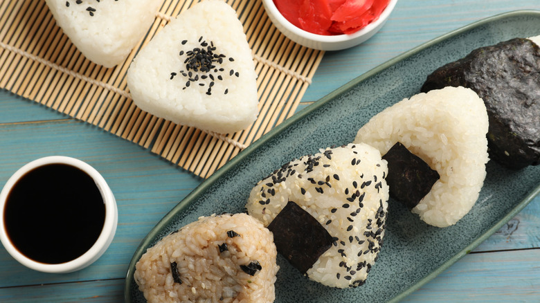 Rice balls (onigiri), soy sauce and pickled ginger on light blue wooden table