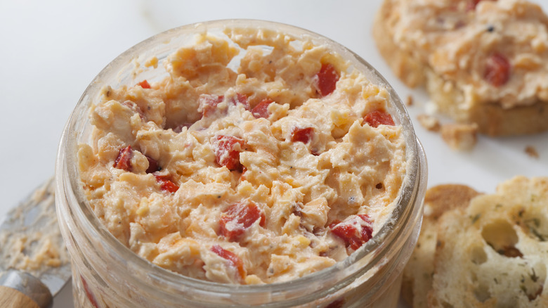 Pimento cheese in a jar on a white surface