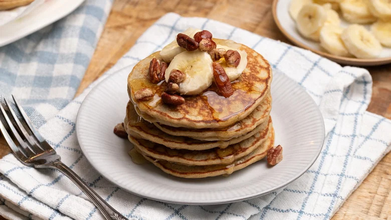 Banana pancakes on a white plate with nuts