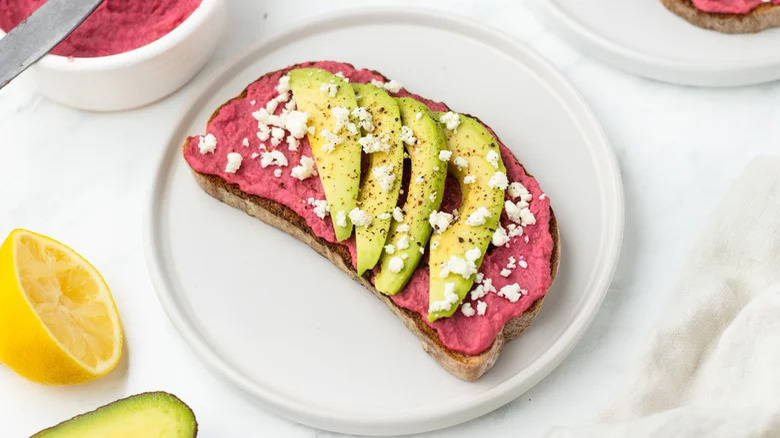 Beeroot hummus toast on a plate with avocado