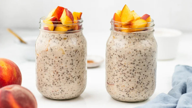 Jars of peach overnight oats on white surface