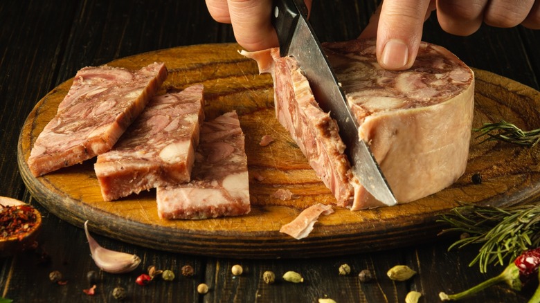 Person slicing head cheese on cutting board