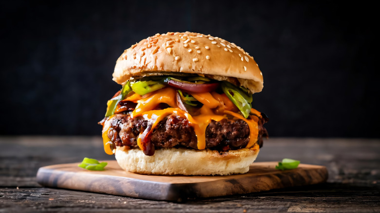 Burger with cheese and jalapeños on wooden surface