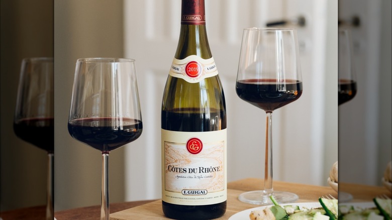 A bottle of E. Guigal Côtes du Rhône Rouge on a table with two glasses of wine