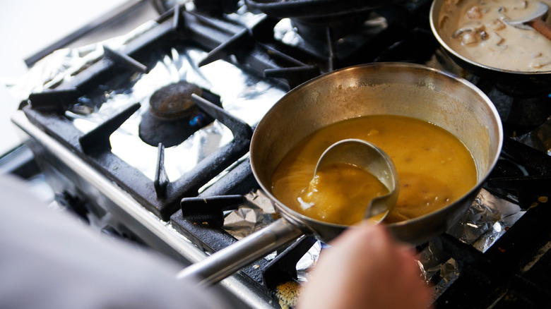 A person making a pan sauce on a stove