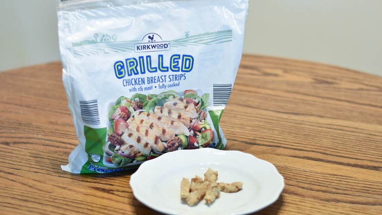 A bag of Aldi grilled chicken breast strips next to a white plate of prepared chicken