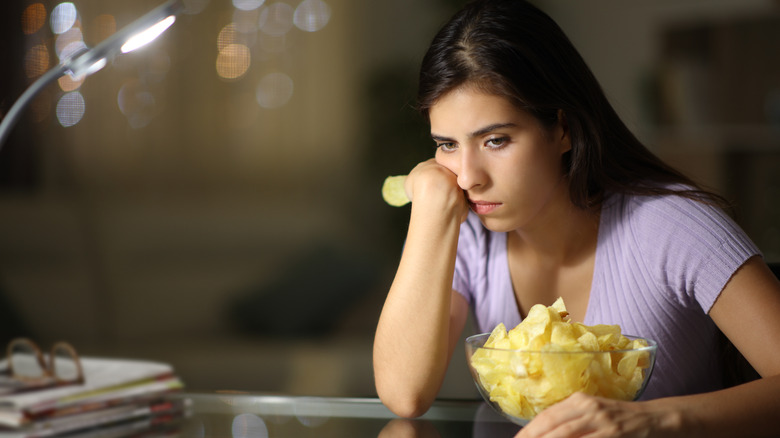 Unhappy woman with a bowl of chips