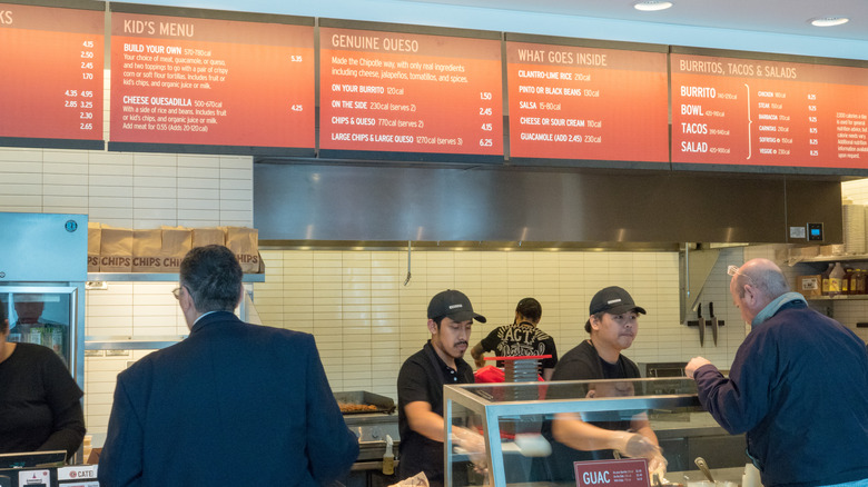 Some men ordering meals at a Chipotle as employees create their order