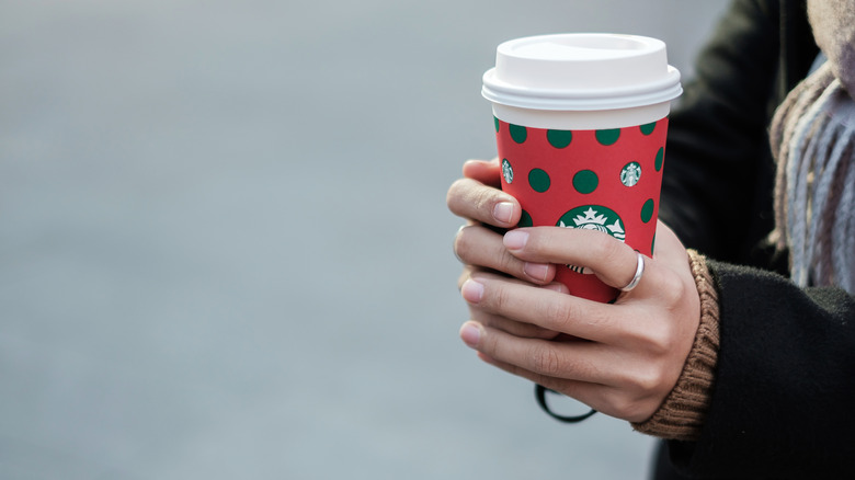 Hands holding one of Starbucks' holiday cups