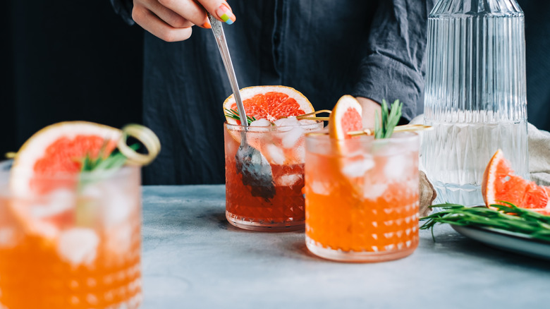 Person making drinks at a bar with grapefruit