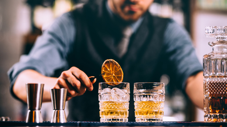 Bartender making a cocktail at a bar with an orange garnish