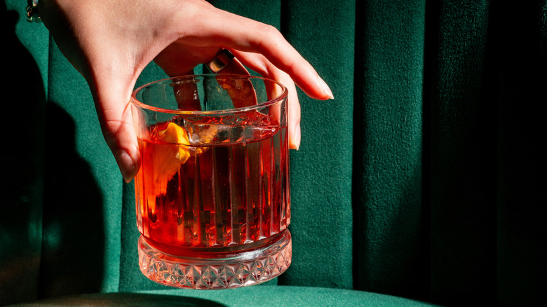 Person placing a Negroni glass down