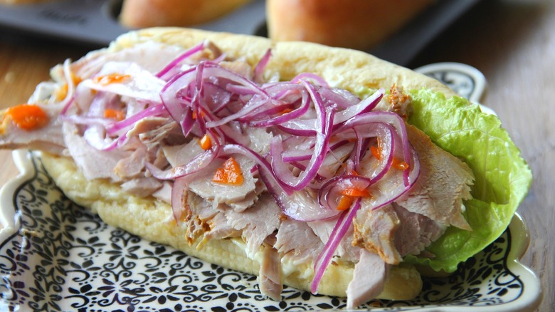 A butifarra sandwich topped with salsa criolla