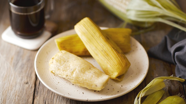 Humitas on a plate with a cup of black coffee